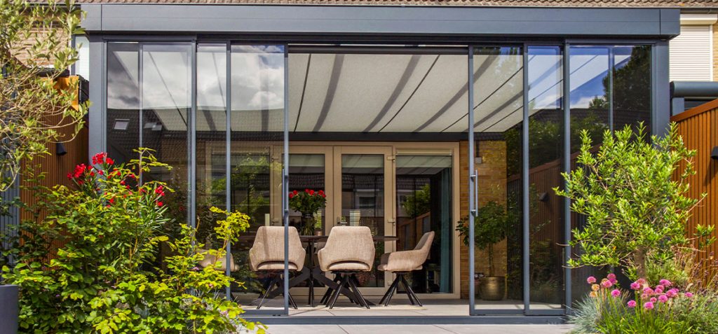 Overkapping met glazen schuifwanden en geïntegreerde onderdakzonwering – Van Beem Buitenleven