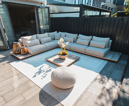 Suns Aspen loungeset in hoekopstelling met kleed en poef in stijlvolle tuinsetting