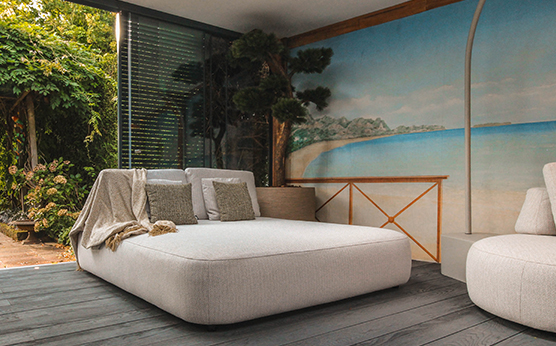 Suns Blocchi daybed with decorative cushions in luxurious garden setting – Van Beem Outdoor Living