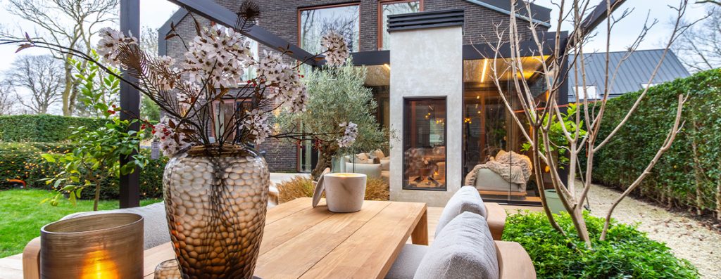 Sfeerbeeld van Renson overkapping met canvas dak, lamellendak, glasschuifwanden en pergola – Van Beem Buitenleven