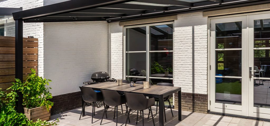 Overkapping met glazen dak en LED spotverlichting – sfeervolle buitenruimte – Van Beem Buitenleven